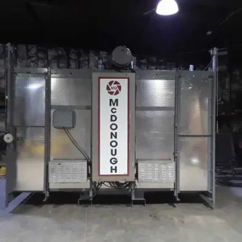 ONEMcDonough One McDonough industrial machine stands indoors on a concrete floor under overhead lighting, its name clearly displayed on the front sign.