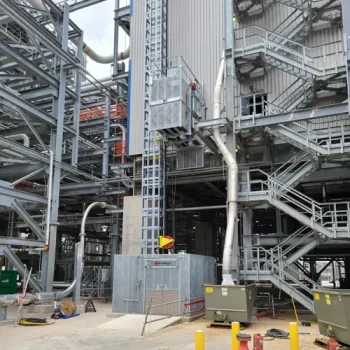 ONEMcDonough Industrial facility with metal staircases, platforms, and piping, featuring various machinery and utility boxes at ground level—ideal for projects like elevator refurbishment.